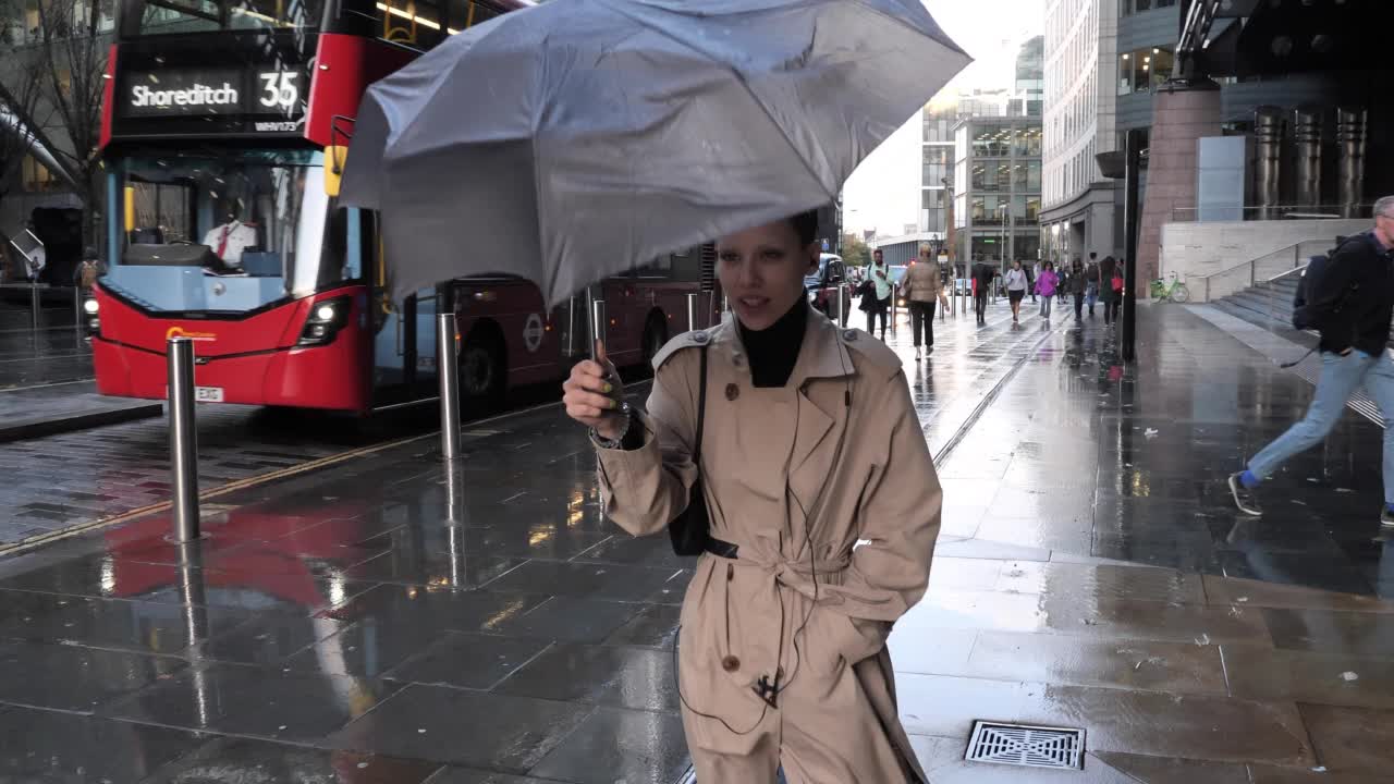 短发女人在刮风下雨的日子打着伞视频素材