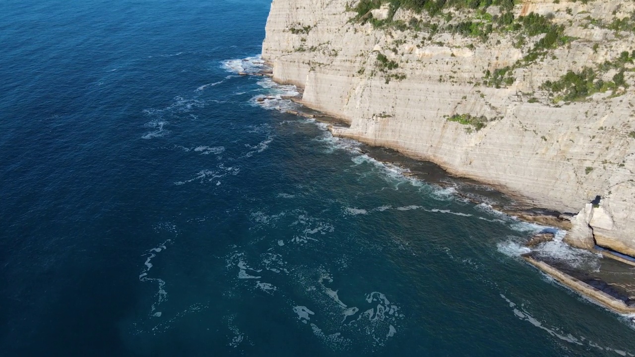 从空中俯瞰，海浪拍打着蓝色海洋中的岩石。海浪在美丽的海滩鸟瞰图无人机。从上方鸟瞰海浪撞击空岩悬崖的景象。视频素材