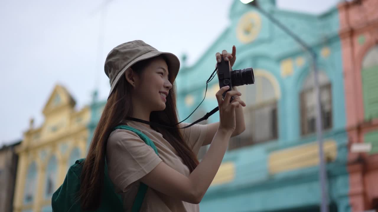 亚洲年轻女性背包客使用相机拍摄地点，同时旅行与快乐的情感表达，独自旅行在生活方式度假夏天。视频素材