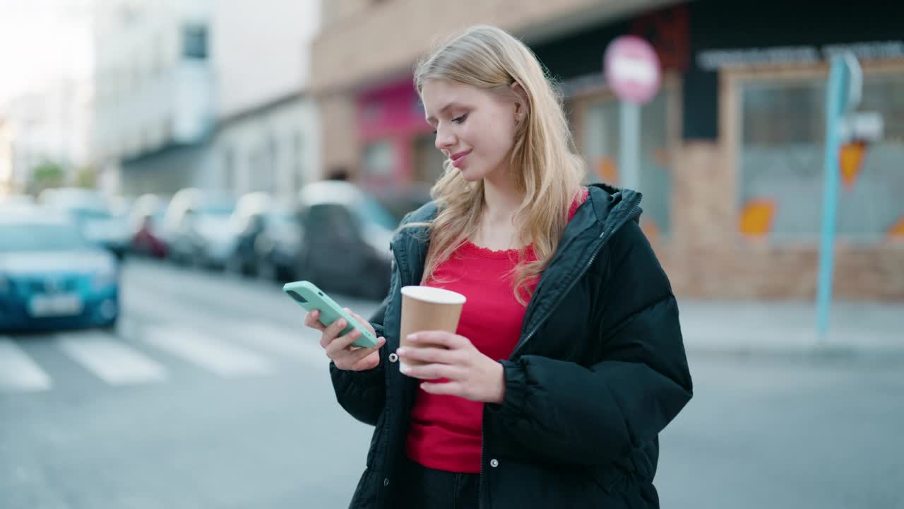 年轻的金发女孩在街上用智能手机喝咖啡视频素材