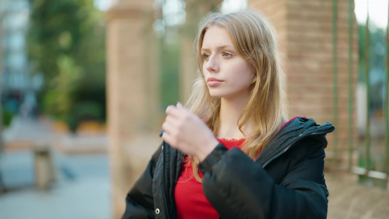 年轻的金发女孩自信地微笑着站在街上视频素材