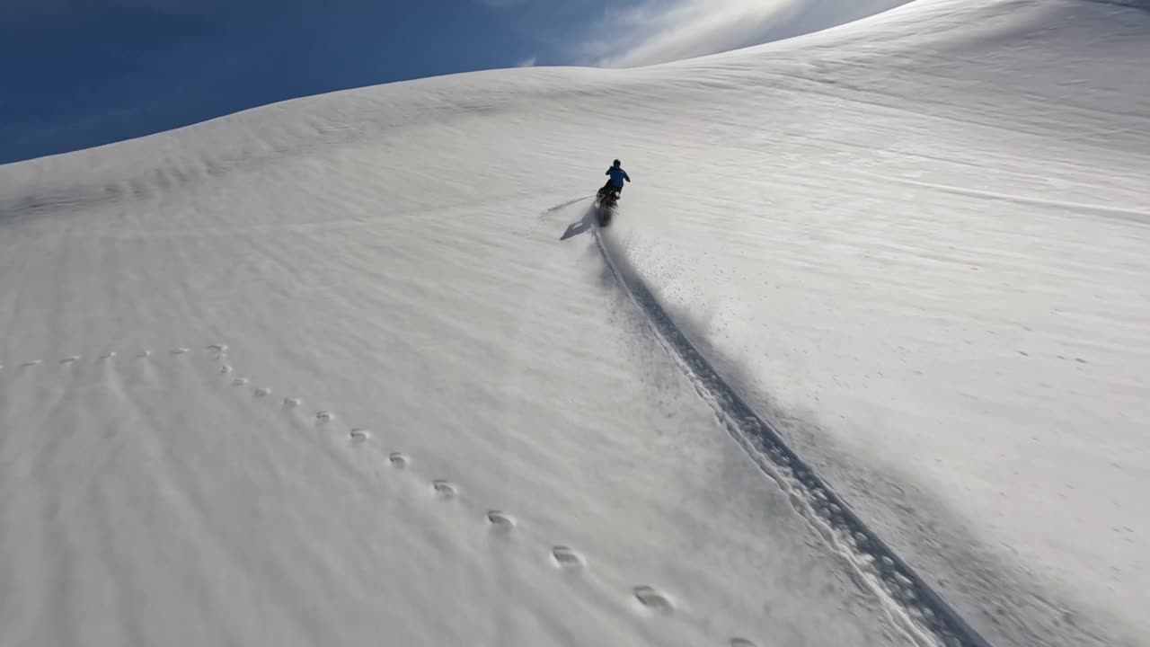 航拍男子极限骑着雪上自行车被雪坡山包围视频素材