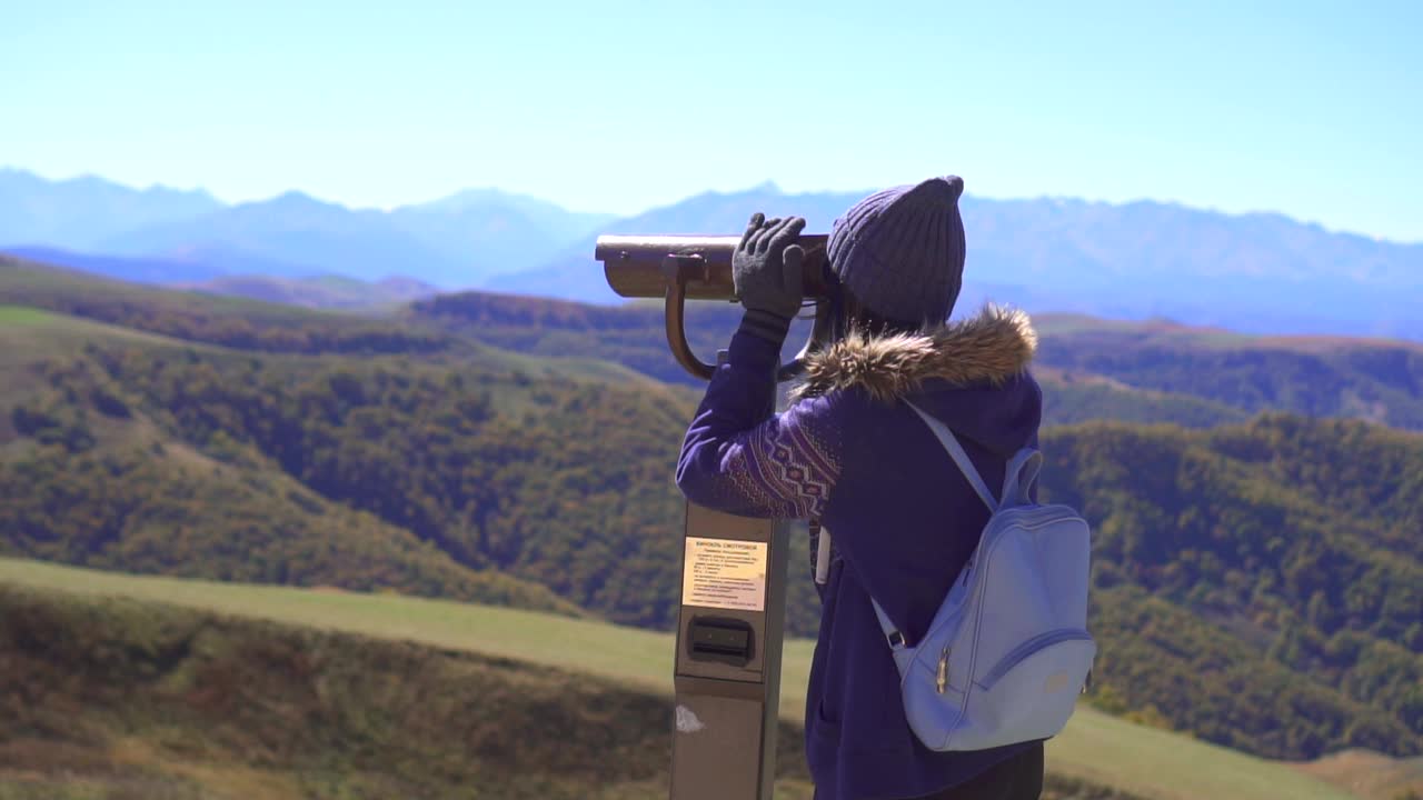 旅游女孩背着背包在观景台上用望远镜看山，慢悠悠莫视频素材