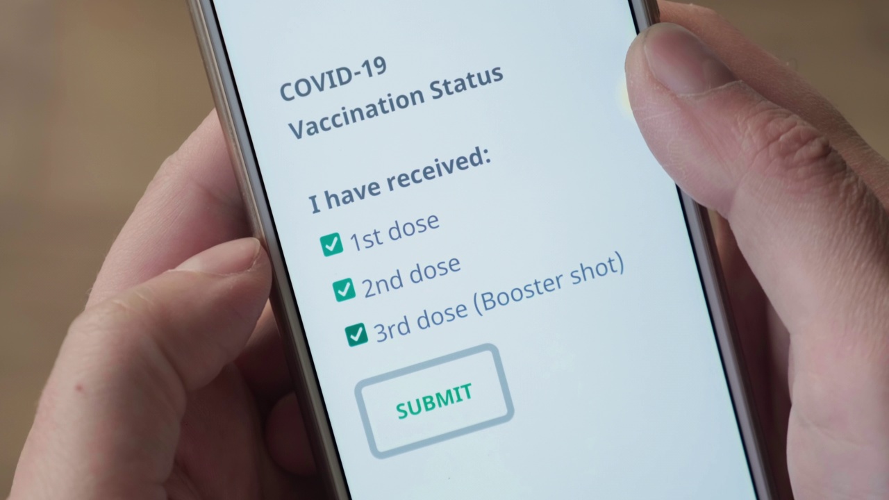 手在手机屏幕上滴答滴答地打第一、第二和第三针(加强针)的Covid-19疫苗接种情况视频下载