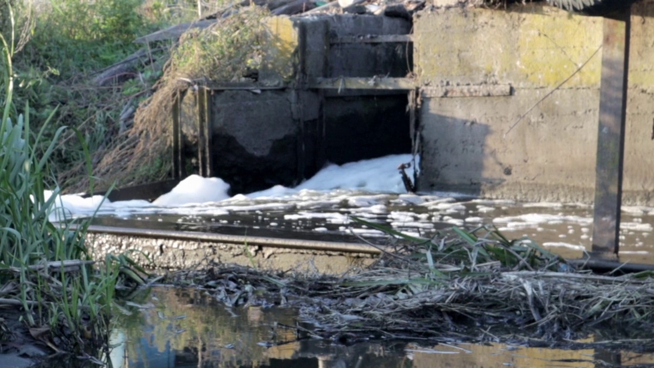 城市的排水沟和污水慢慢地流入河中。污水从城市流入下水道。水污染和工业污水。被污染的水道景色不错。使用的水视频素材