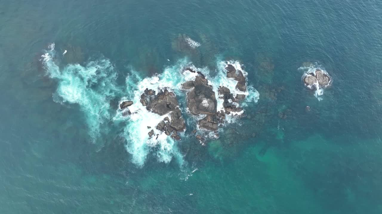 海浪撞击着海洋中的岩石。一幅宁静的自然景象。水中岩石的鸟瞰图。海洋与陆地的交汇处。慢动作120帧的视频视频素材