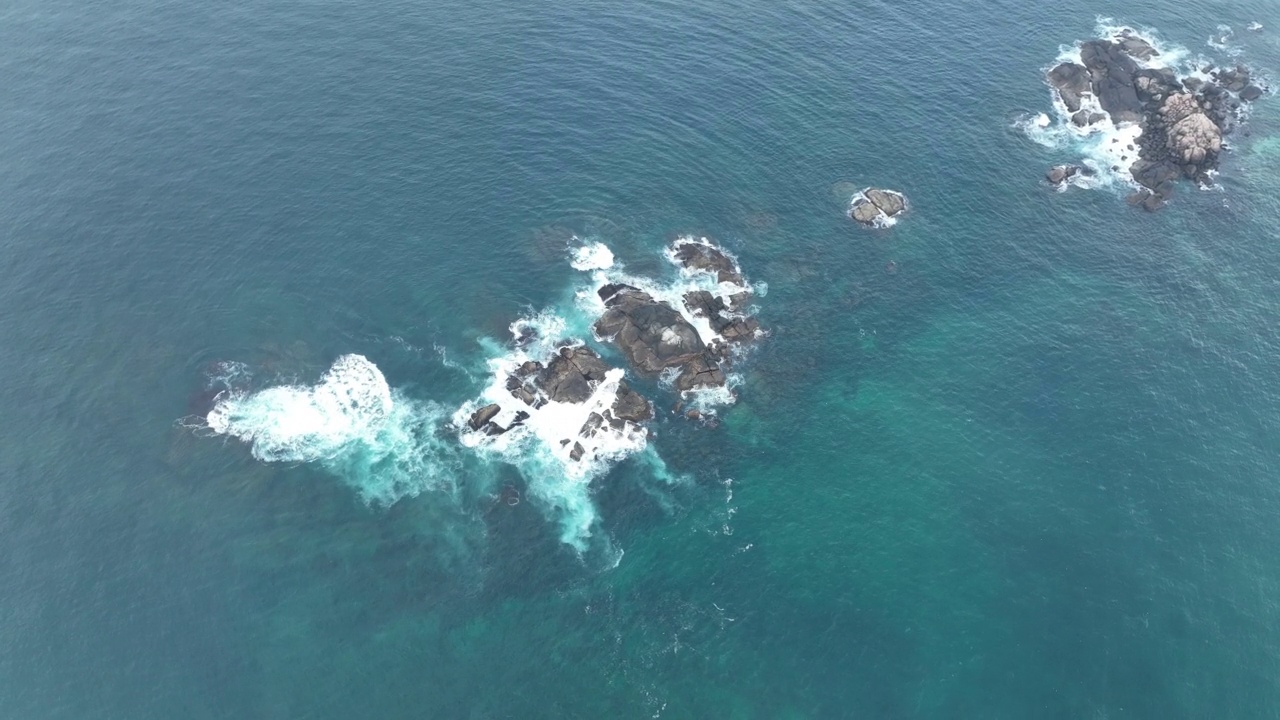 海浪撞击着海洋中的岩石。一幅宁静的自然景象。水中岩石的鸟瞰图。海洋与陆地的交汇处。慢动作120帧的视频视频素材