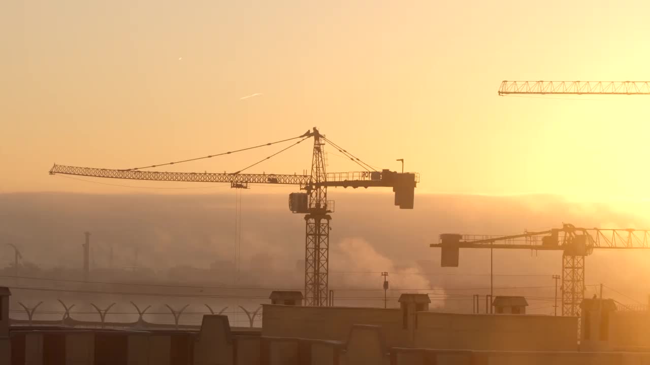 建筑工地上的起重机在工厂城市的背景下举起货物视频素材