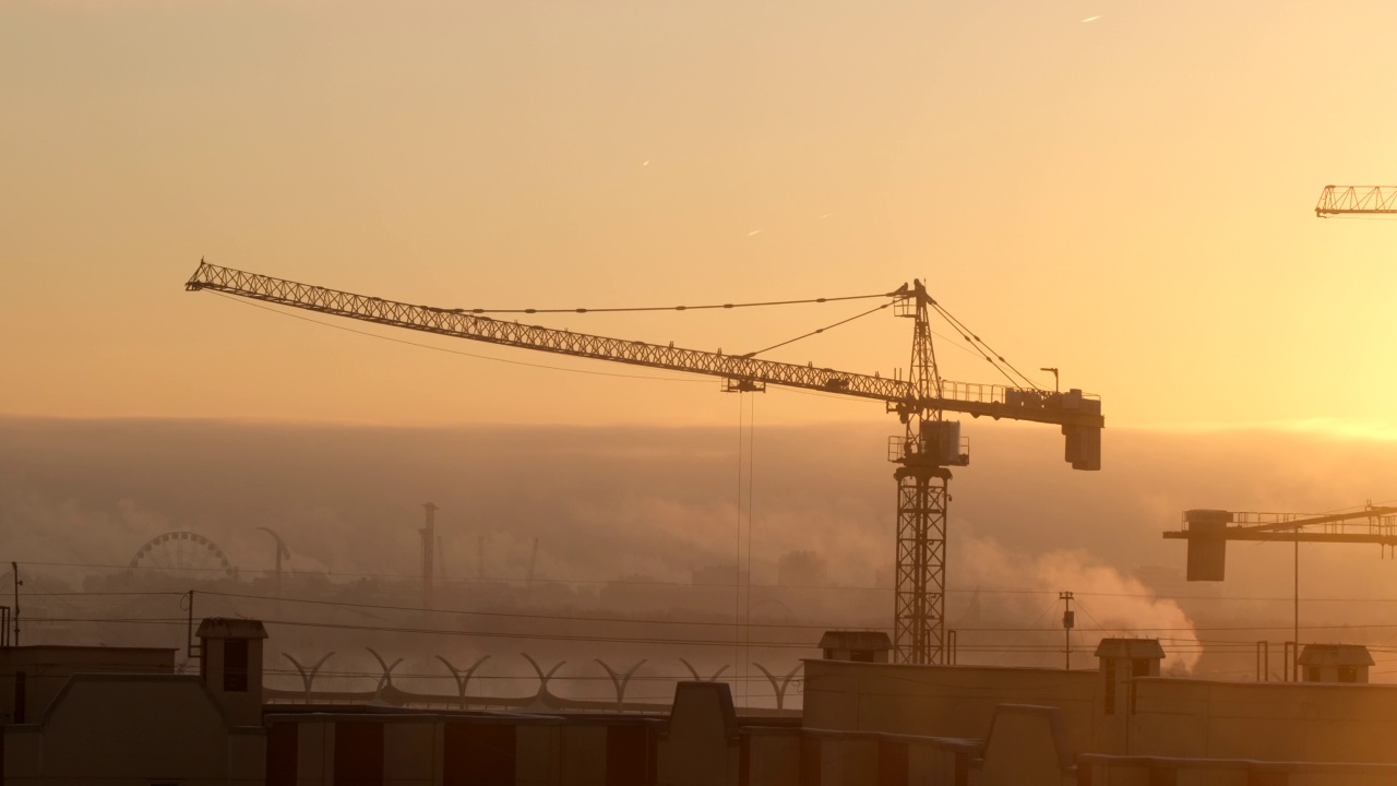 建筑工地上的起重机在工厂城市的背景下举起货物视频素材