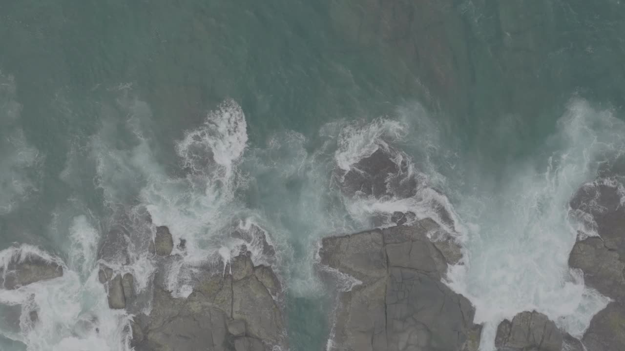 海浪撞击着海洋中的岩石。一幅宁静的自然景象。水中岩石的鸟瞰图。海洋与陆地的交汇处。120fps视频，ProRes, 10bit，未分级D-LOG视频素材