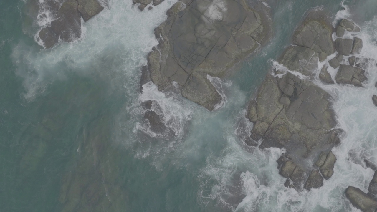 海浪撞击着海洋中的岩石。一幅宁静的自然景象。水中岩石的鸟瞰图。海洋与陆地的交汇处。120fps视频，ProRes, 10bit，未分级D-LOG视频素材