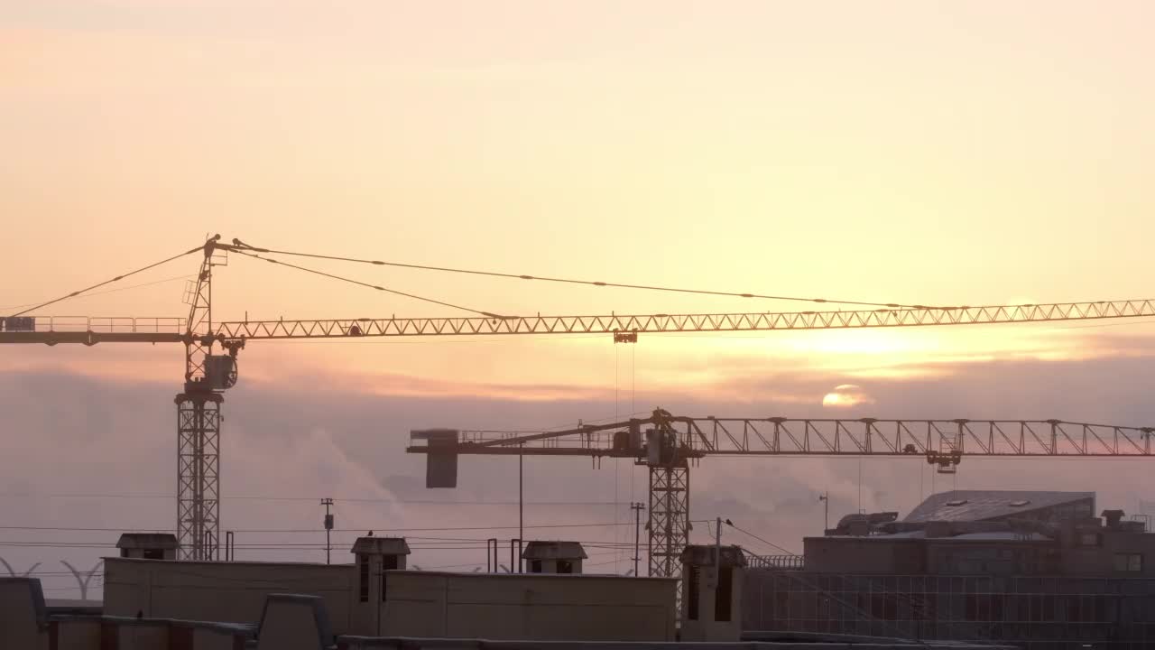 建筑工地上的起重机在城市背景下吊起货物，雾中的工厂视频素材