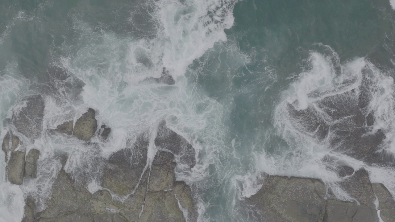 海浪撞击着海洋中的岩石。一幅宁静的自然风景。水中岩石的鸟瞰图。海洋和陆地的交汇处。120fps视频，ProRes, 10位，未分级D-LOG视频素材