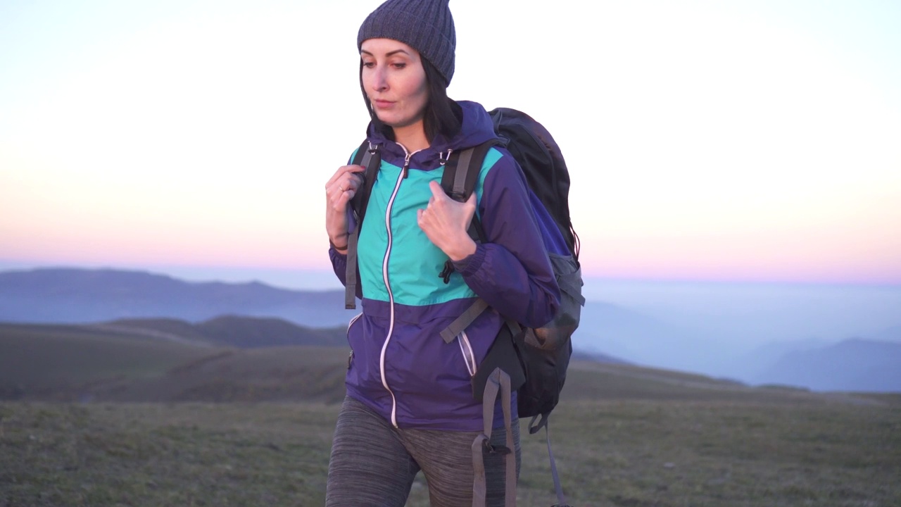 女孩背着大背包在山上登山，日出视频素材