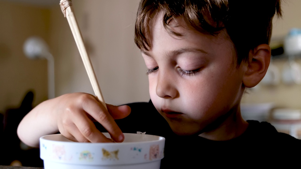 小男孩在自家厨房用筷子吃米饭视频素材