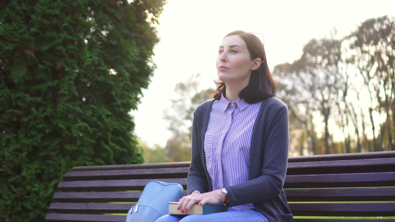 一个有视力障碍的女孩在长椅上用手指读着布莱叶盲文写的书视频素材