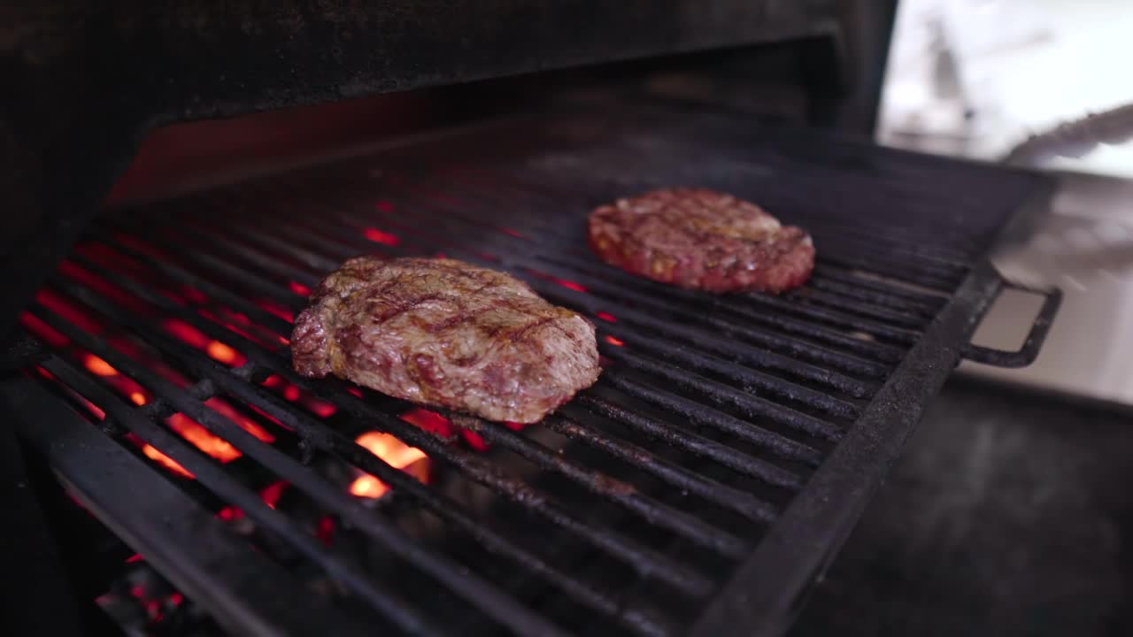 厨师在餐馆里翻动烤牛排。用夹子在烤架上烤肉。烧烤烹饪美味的视频素材