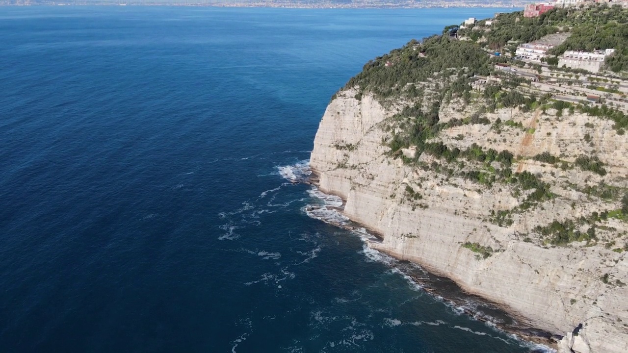 从空中俯瞰，海浪拍打着蓝色海洋中的岩石。海浪在美丽的海滩鸟瞰图无人机。从上方鸟瞰海浪撞击空岩悬崖的景象。视频素材