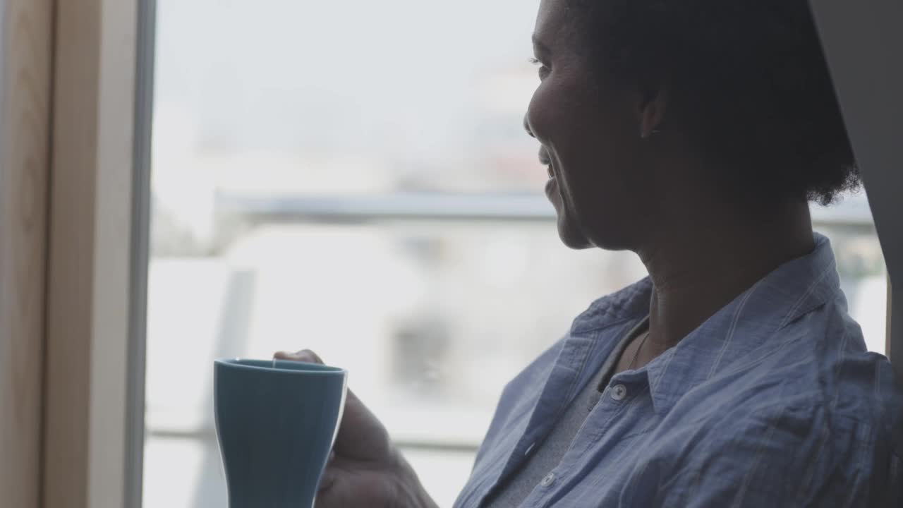 视频肖像的女人放松在窗台上，看外面，喝着茶视频素材