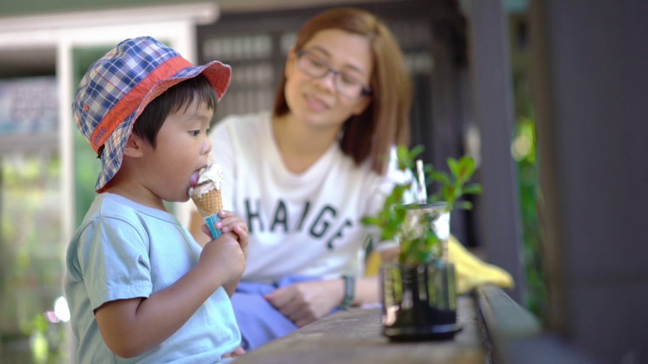 母子俩在户外的一家咖啡馆里享用甜筒冰淇淋。视频素材