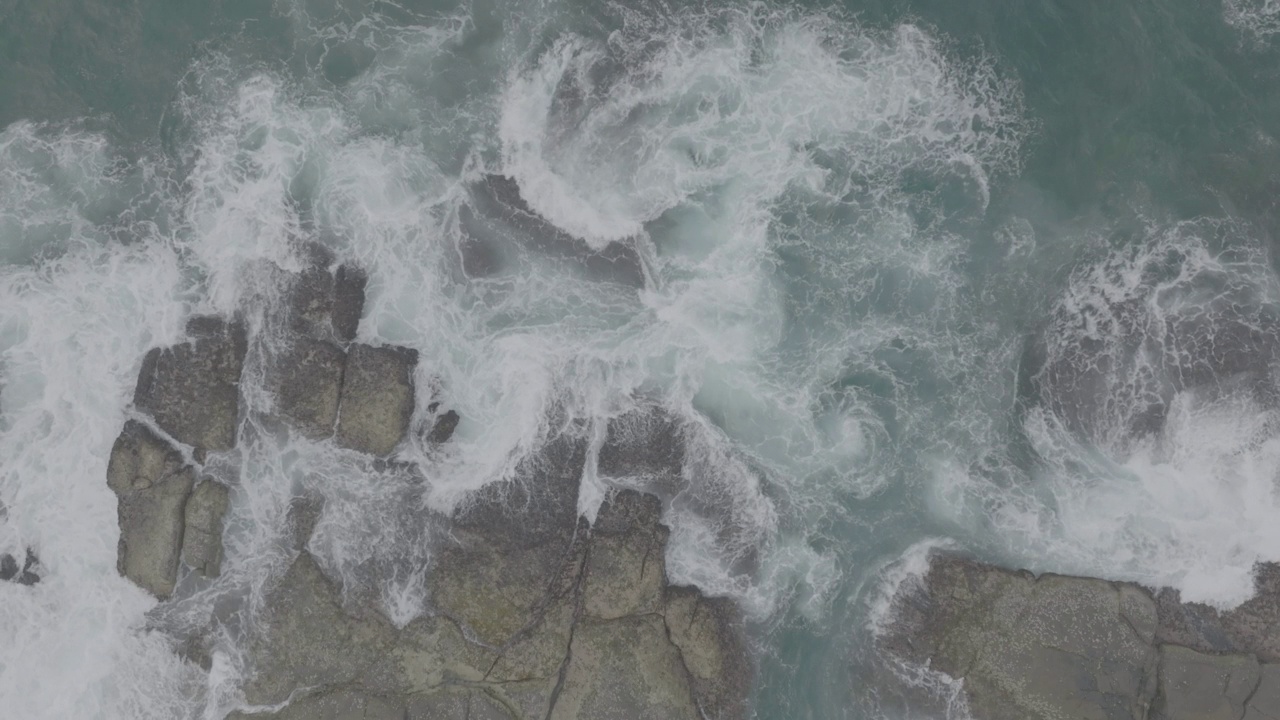 海浪撞击着海洋中的岩石。一幅宁静的自然风景。水中岩石的鸟瞰图。海洋和陆地的交汇处。120fps视频，ProRes, 10位，未分级D-LOG视频素材