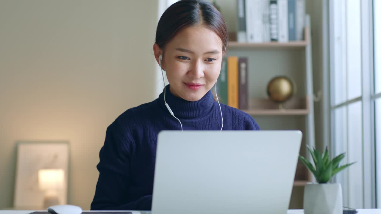 年轻的亚洲女性创造者通过视频电话会议或虚拟会议在家里通过笔记本电脑视频素材