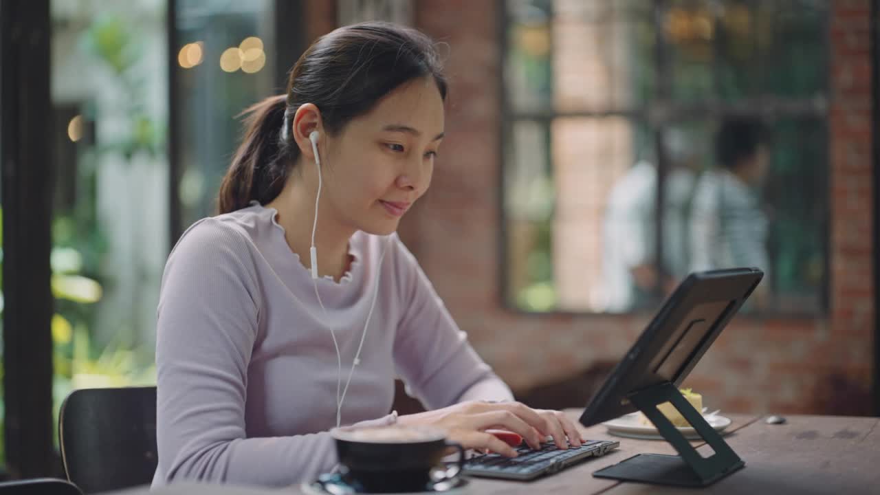 亚洲妇女在咖啡厅用平板电脑聊天视频素材