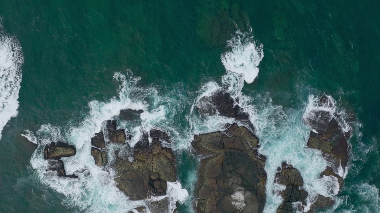 海浪撞击着海洋中的岩石。一幅宁静的自然风景。水中岩石的鸟瞰图。海洋和陆地的交汇处。120帧/秒的视频视频素材