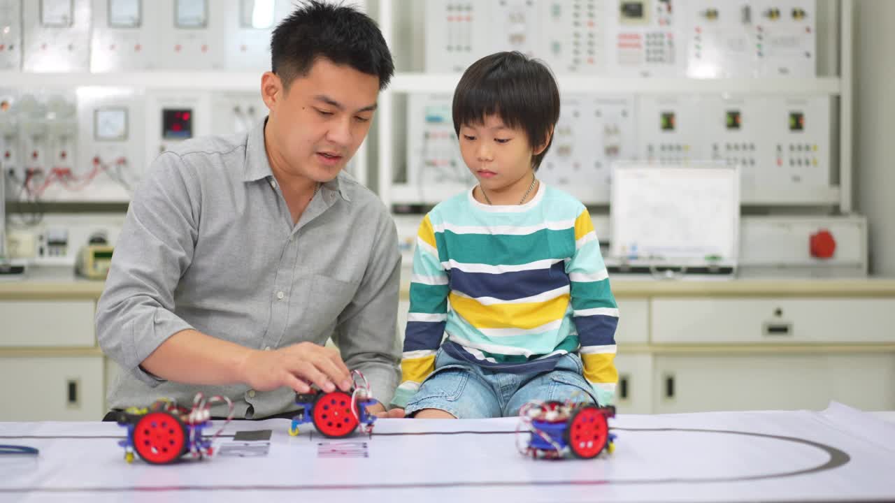 亚洲学生和教师在实验室用传感器响应测试机器人汽车在路线上运行。建筑师设计电路和会议共享技术的想法和协作开发机器人。视频素材