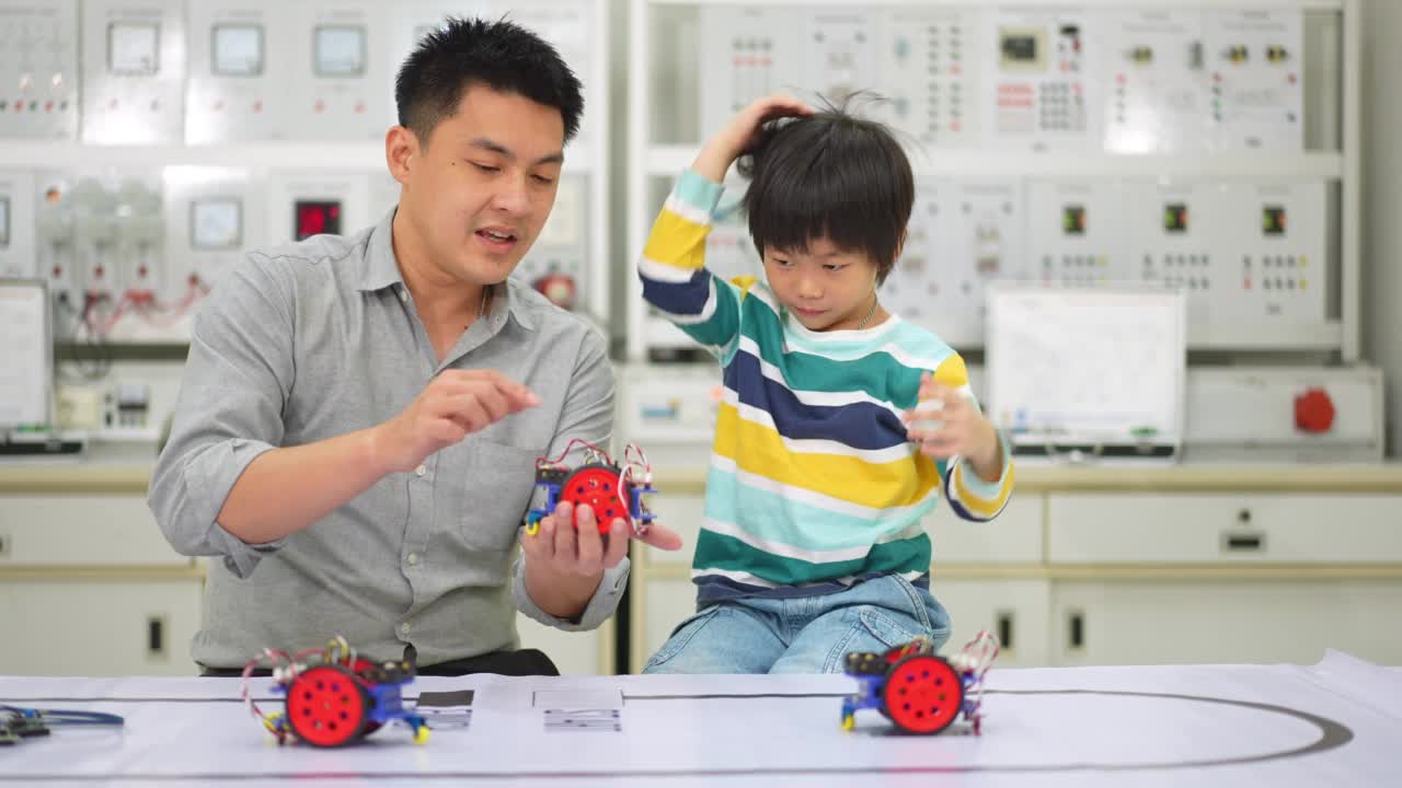 亚洲学生和教师在实验室用传感器响应测试机器人汽车在路线上运行。建筑师设计电路和会议共享技术的想法和协作开发机器人。视频素材