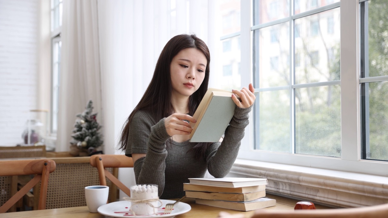 年轻女子在咖啡馆里看书视频素材