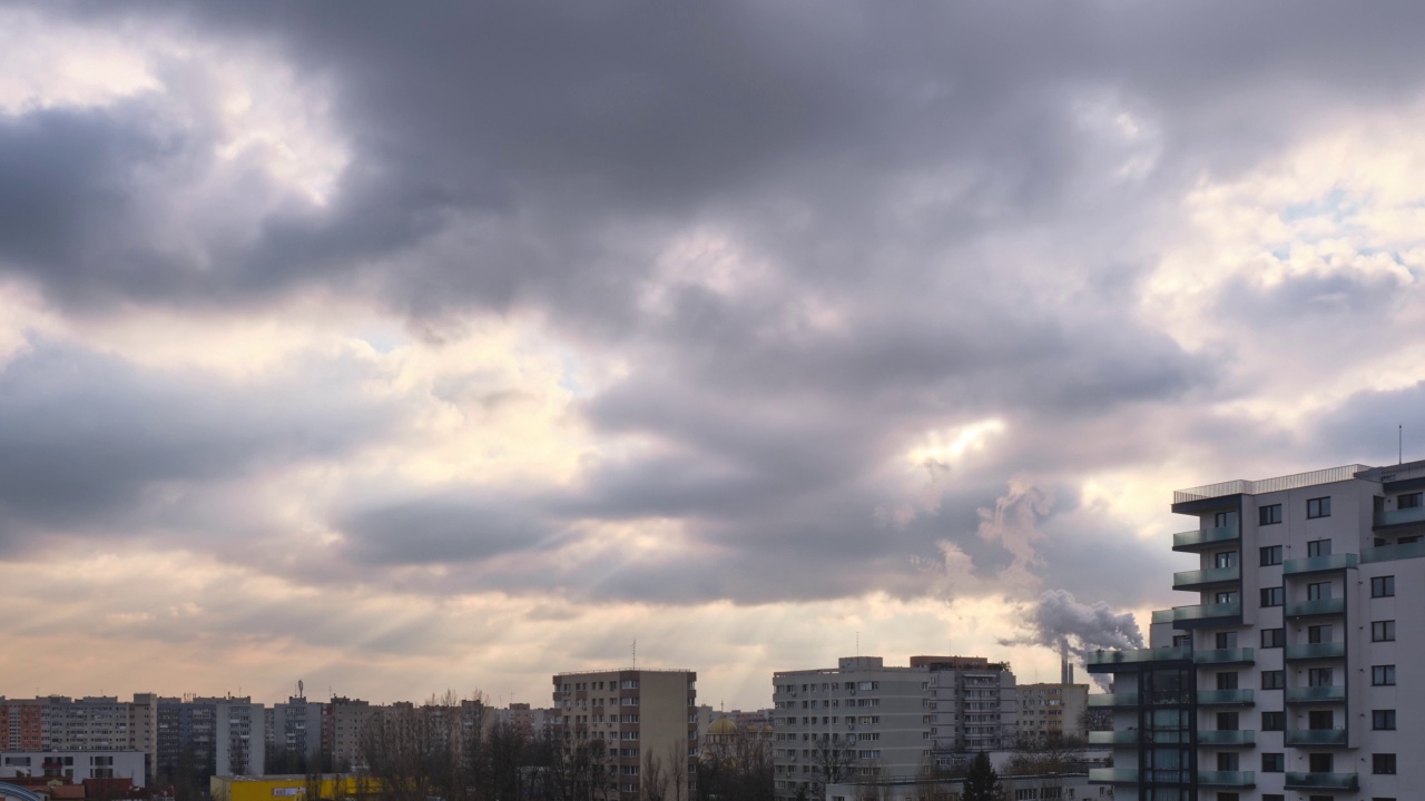 时间流逝的阳光穿过云层，在城市建筑之上。视频下载