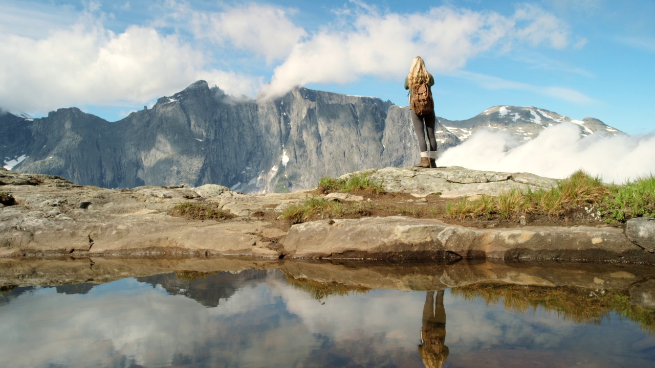 在Møre og Romsdal徒步旅行期间，一名难以辨认的女子欣赏山景的4k视频视频素材