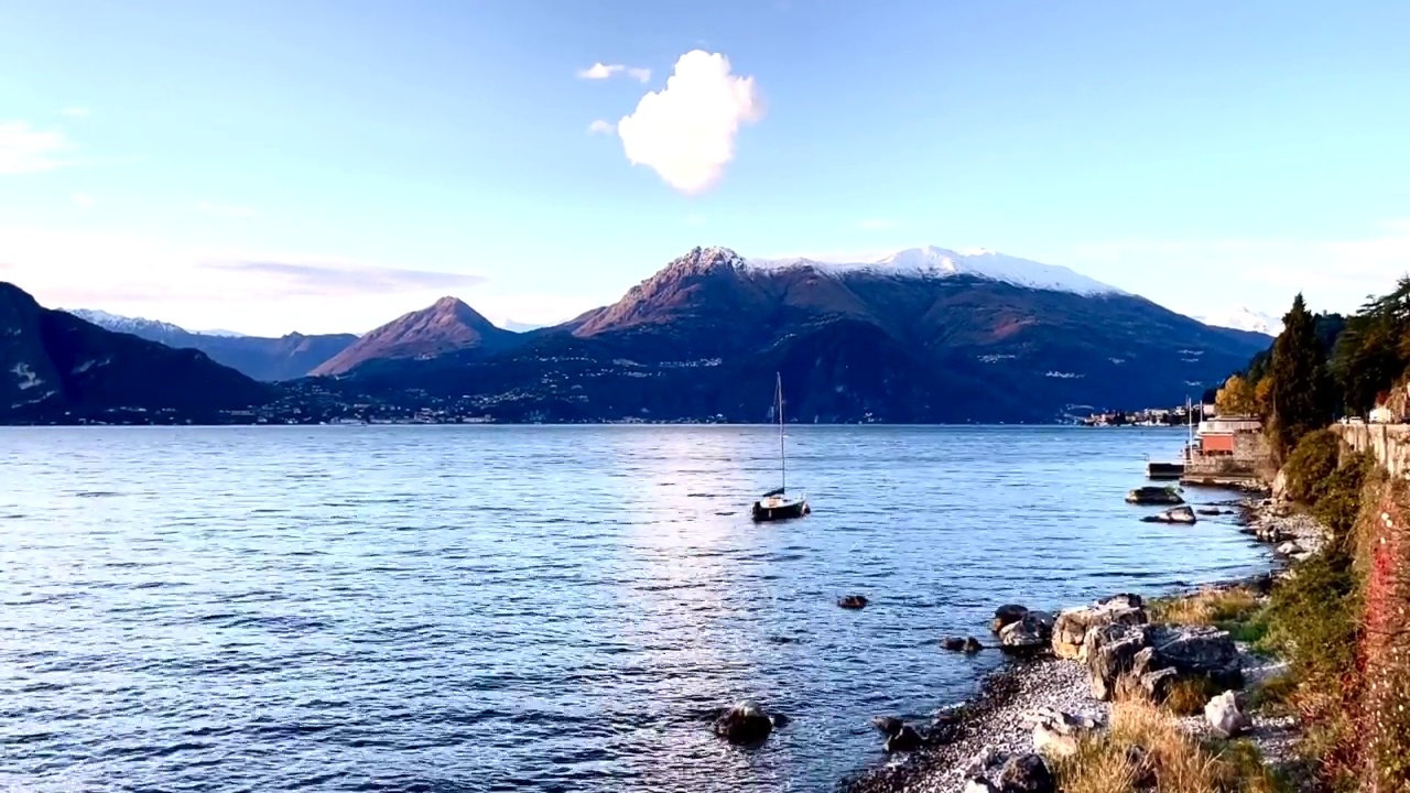 以天空、云和山脉为背景，用延时拍摄的科莫湖，漂浮的游艇。视频素材