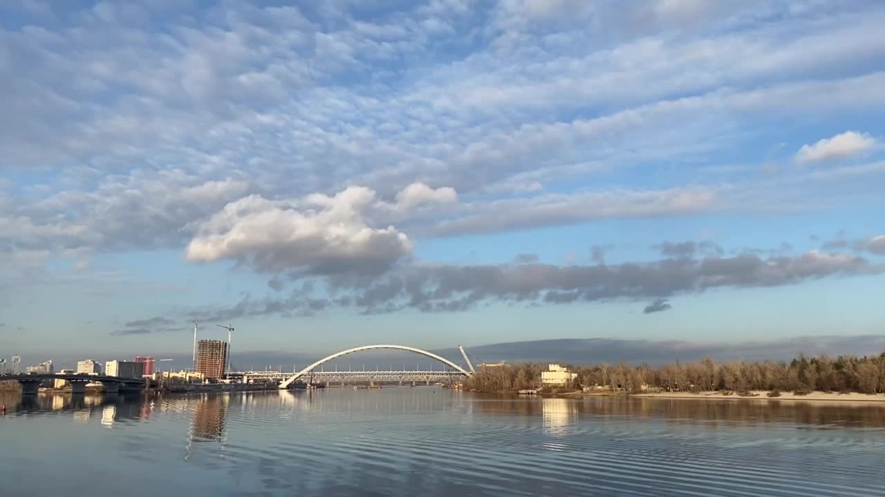 乌克兰首都基辅的城市景观。第聂伯河在阳光明媚的日子里平静湛蓝的河水。壮观的多云的天空。河上有一座现代化的桥。视频素材