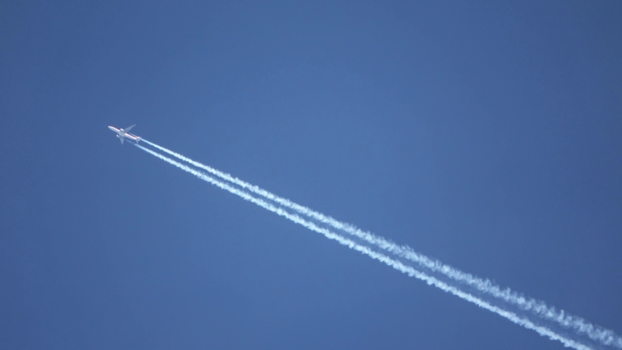 喷气式客机在天空中高高地飞行，在清澈的蓝天上留下了尾迹。视频素材