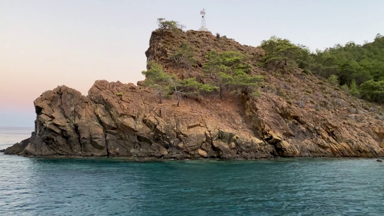 山崖和岩岛在蓝色的海洋景观。蓝色的海水和岸边的岩石峭壁。蓝绿色海洋景观中的落基山脉视频素材