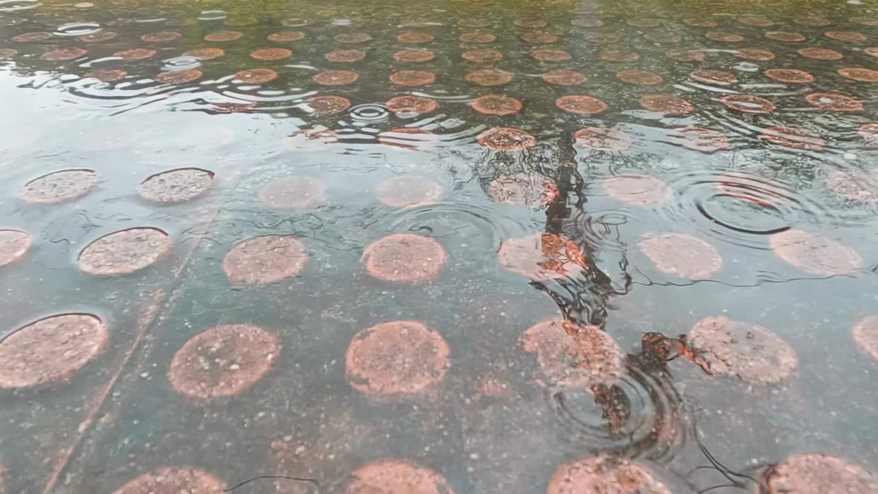 慢动作视频，雨滴落在一个车站站台上的小水坑里，而一列货运火车在水面上倒映视频下载