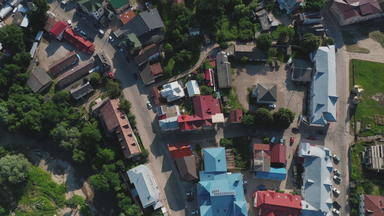 从上往下鸟瞰一个小镇的房屋屋顶，有河流、树木和汽车。视频素材