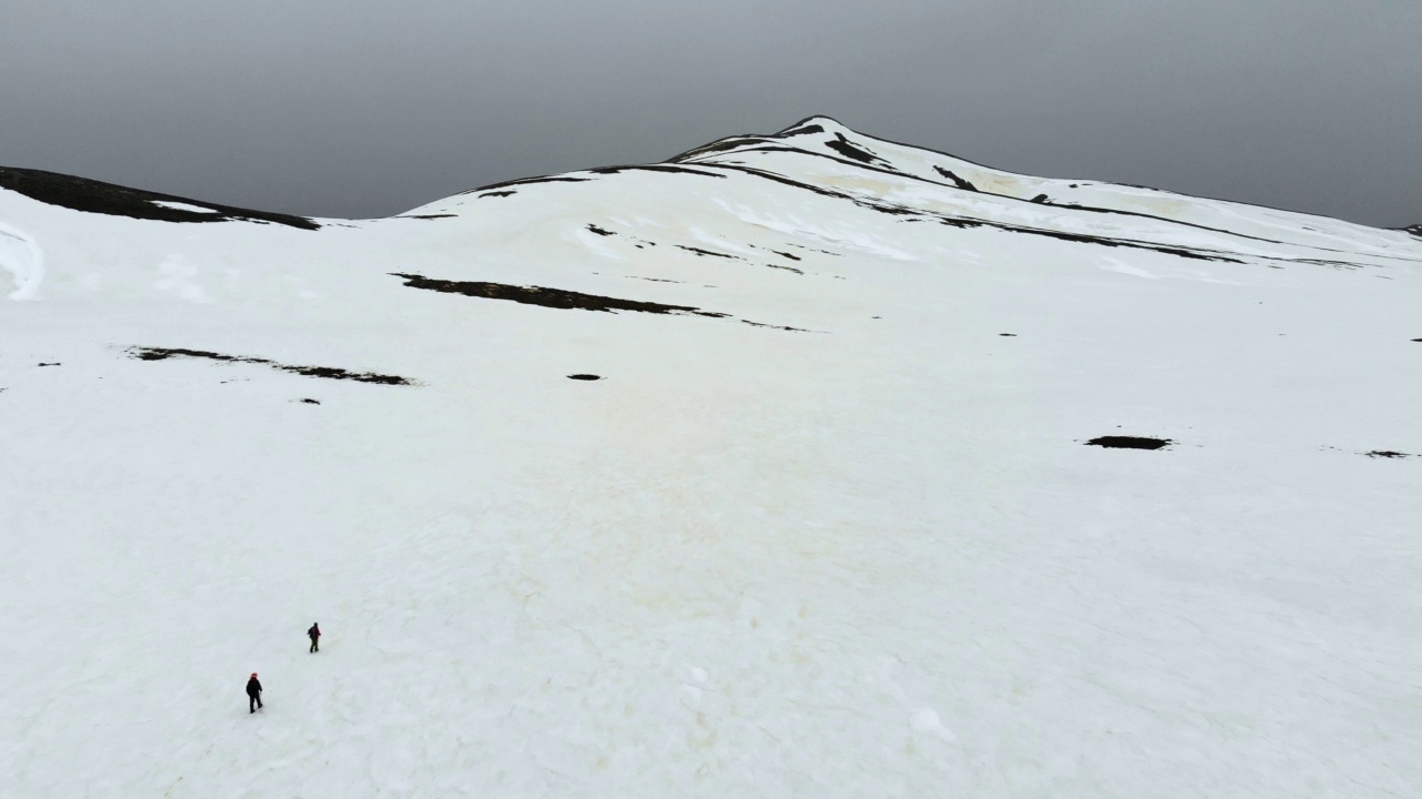 无人机拍摄的成功登山队在冬季在高海拔雪山山顶的山脊上排成一行攀登视频素材