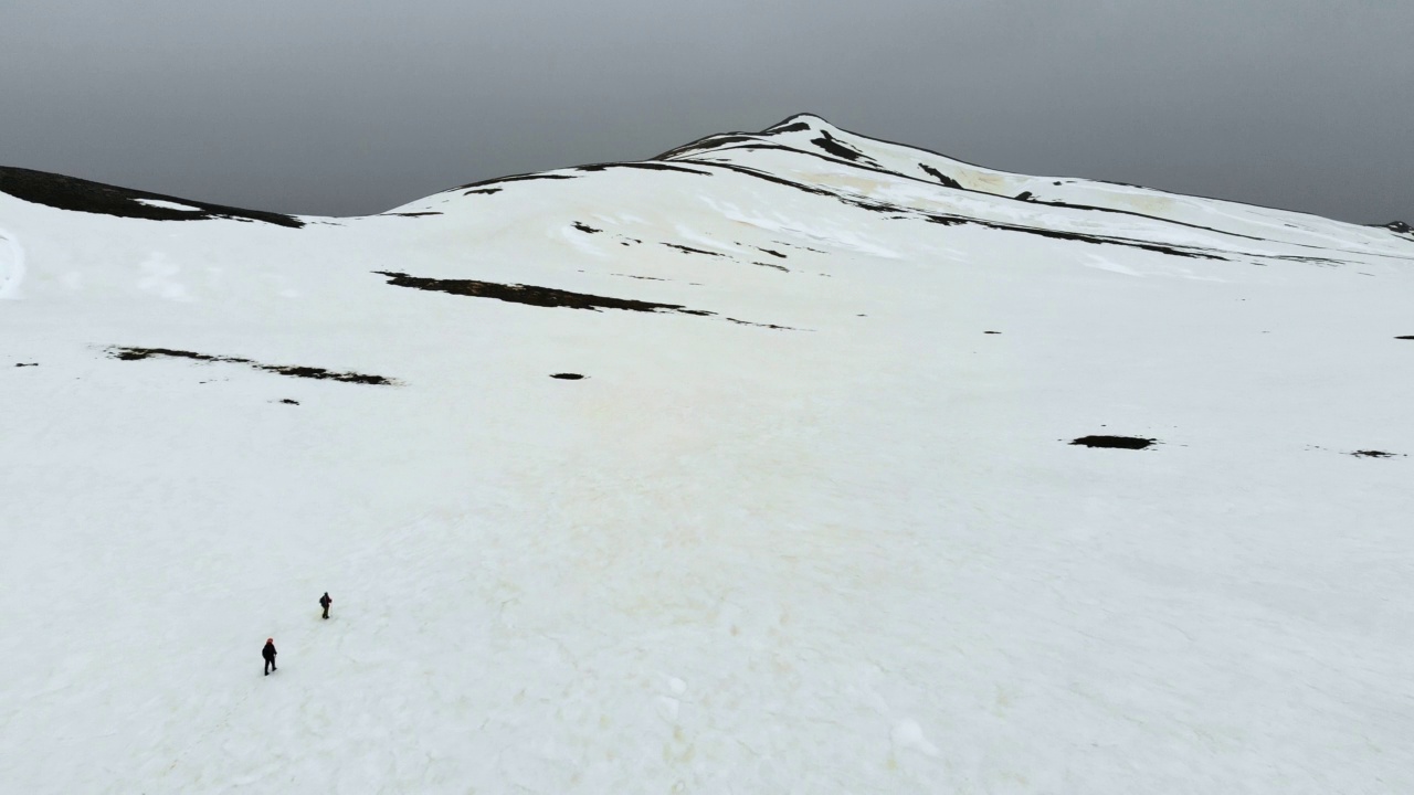 无人机拍摄的成功登山队在冬季在高海拔雪山山顶的山脊上排成一行攀登视频素材