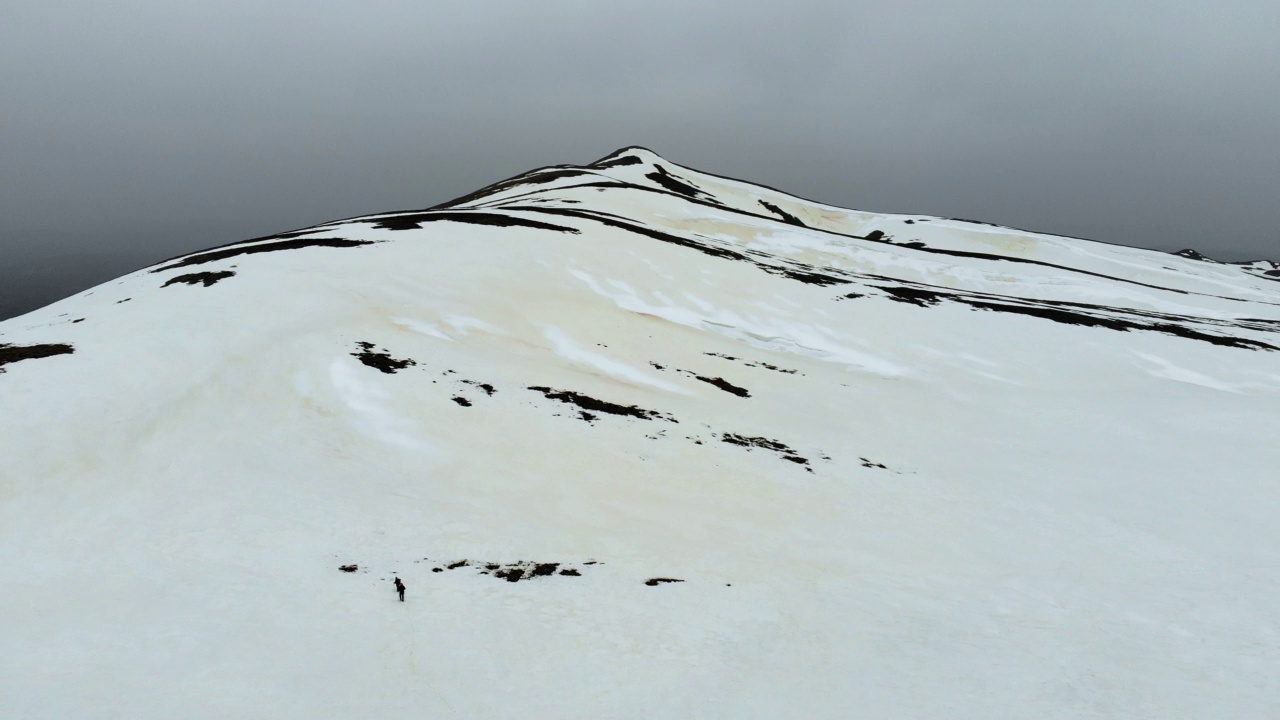 无人机拍摄的成功登山队在冬季在高海拔雪山山顶的山脊上排成一行攀登视频素材