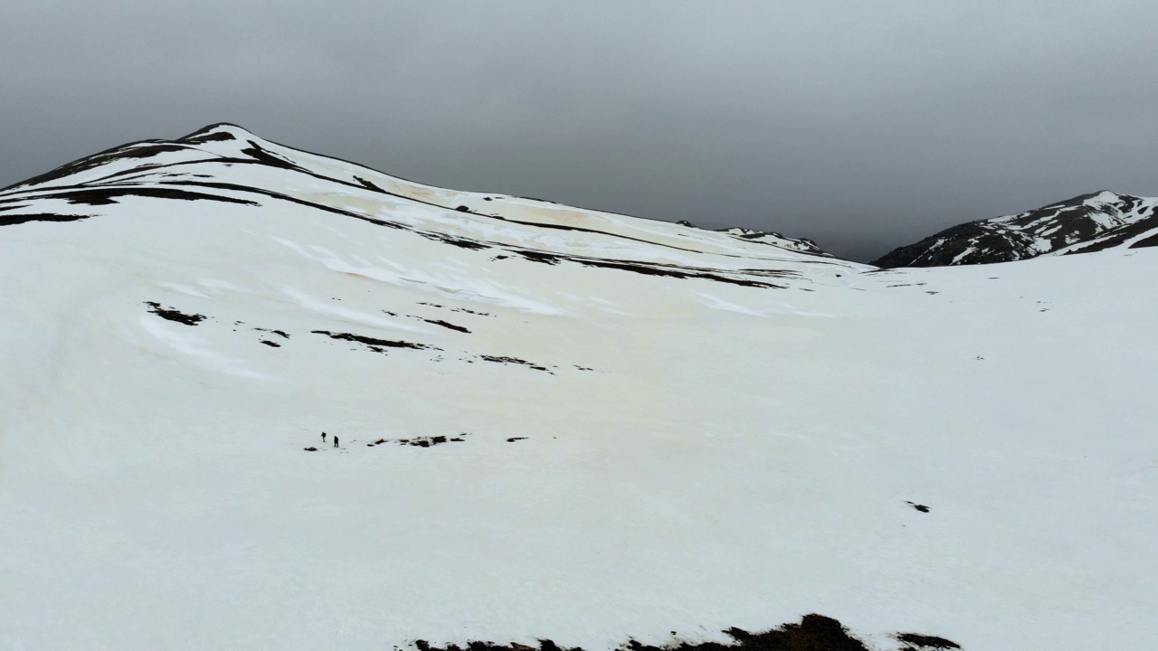 无人机拍摄的成功登山队在冬季在高海拔雪山山顶的山脊上排成一行攀登视频素材