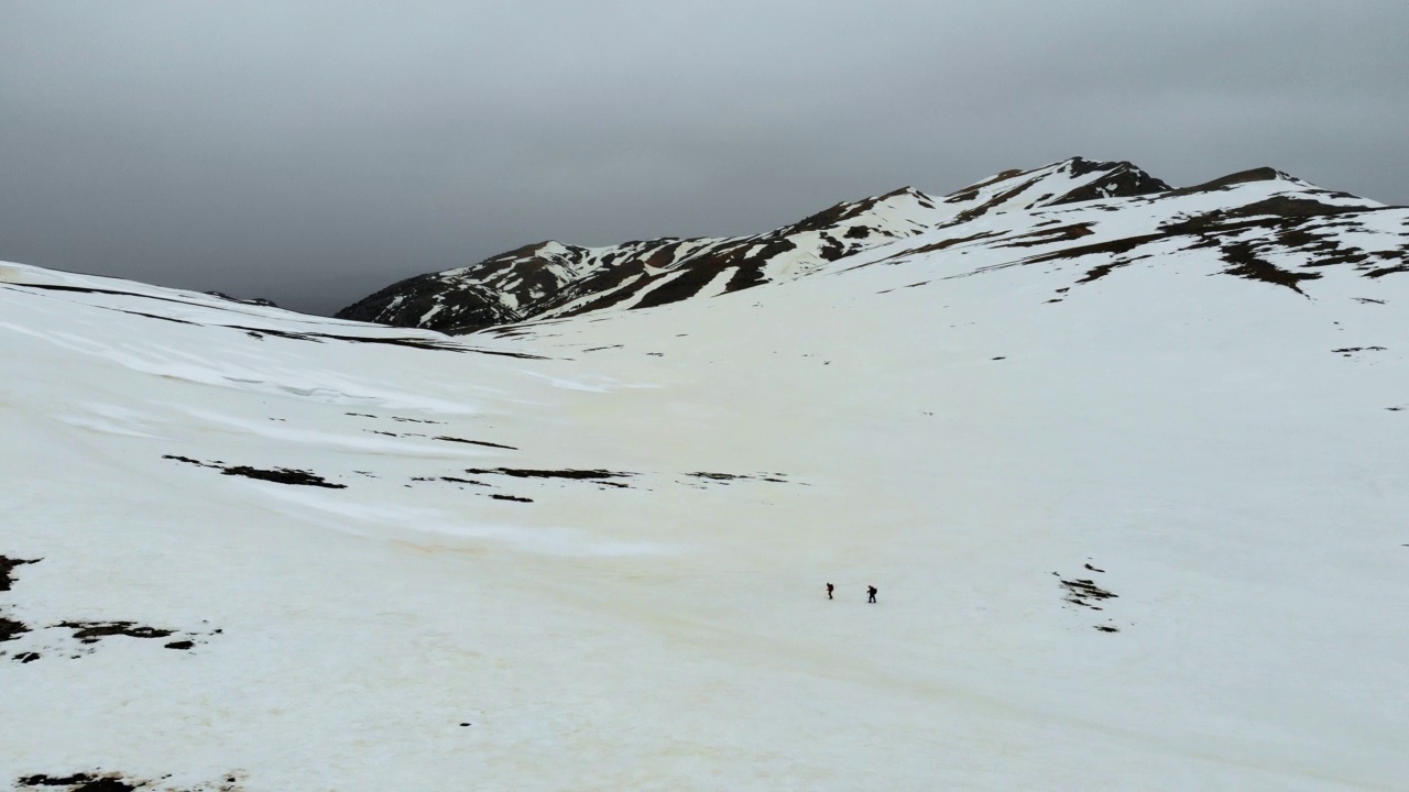 无人机拍摄的成功登山队在冬季在高海拔雪山山顶的山脊上排成一行攀登视频素材