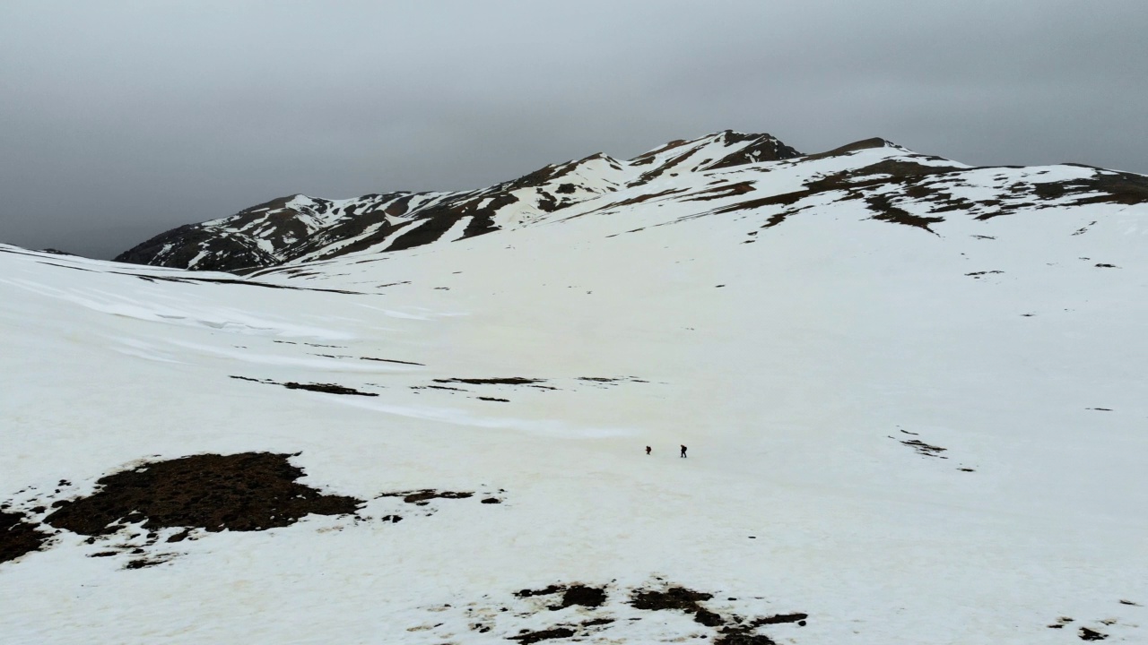 无人机拍摄的成功登山队在冬季在高海拔雪山山顶的山脊上排成一行攀登视频素材