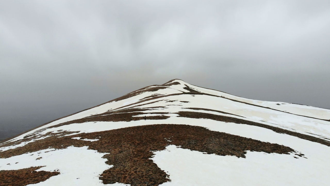 无人机拍摄的成功登山队在冬季在高海拔雪山山顶的山脊上排成一行攀登视频素材