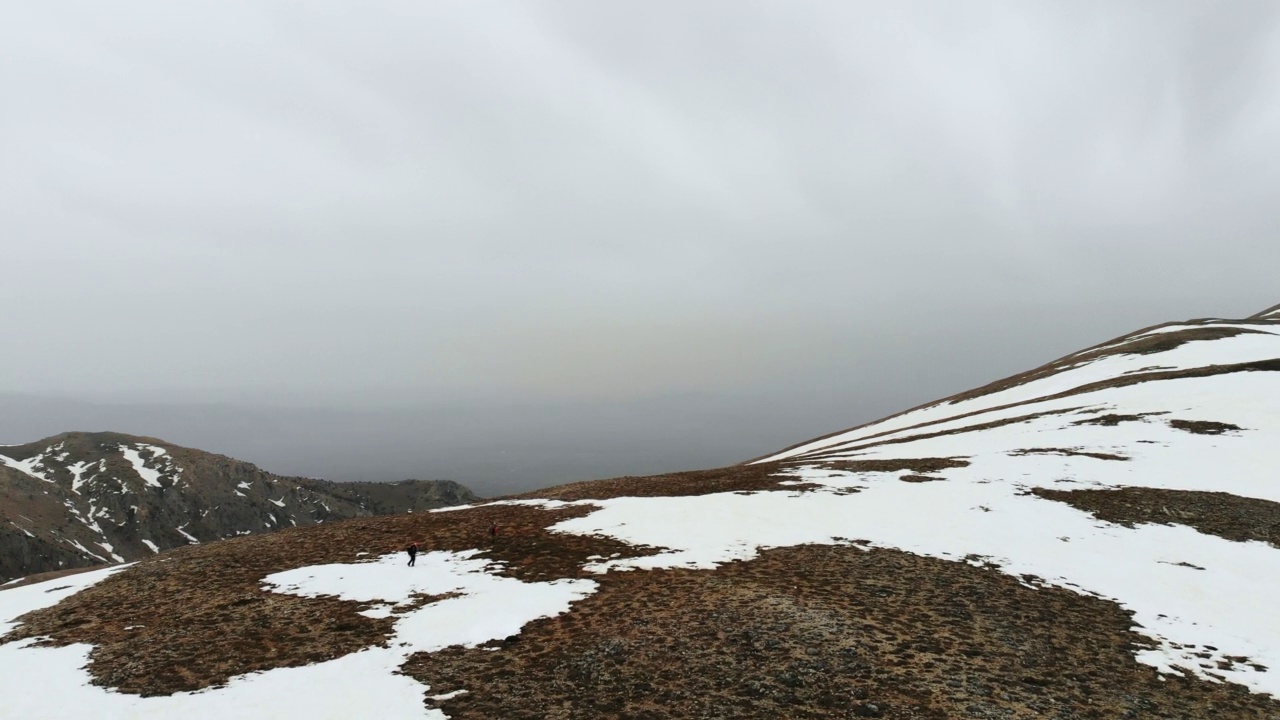 无人机拍摄的成功登山队在冬季在高海拔雪山山顶的山脊上排成一行攀登视频素材