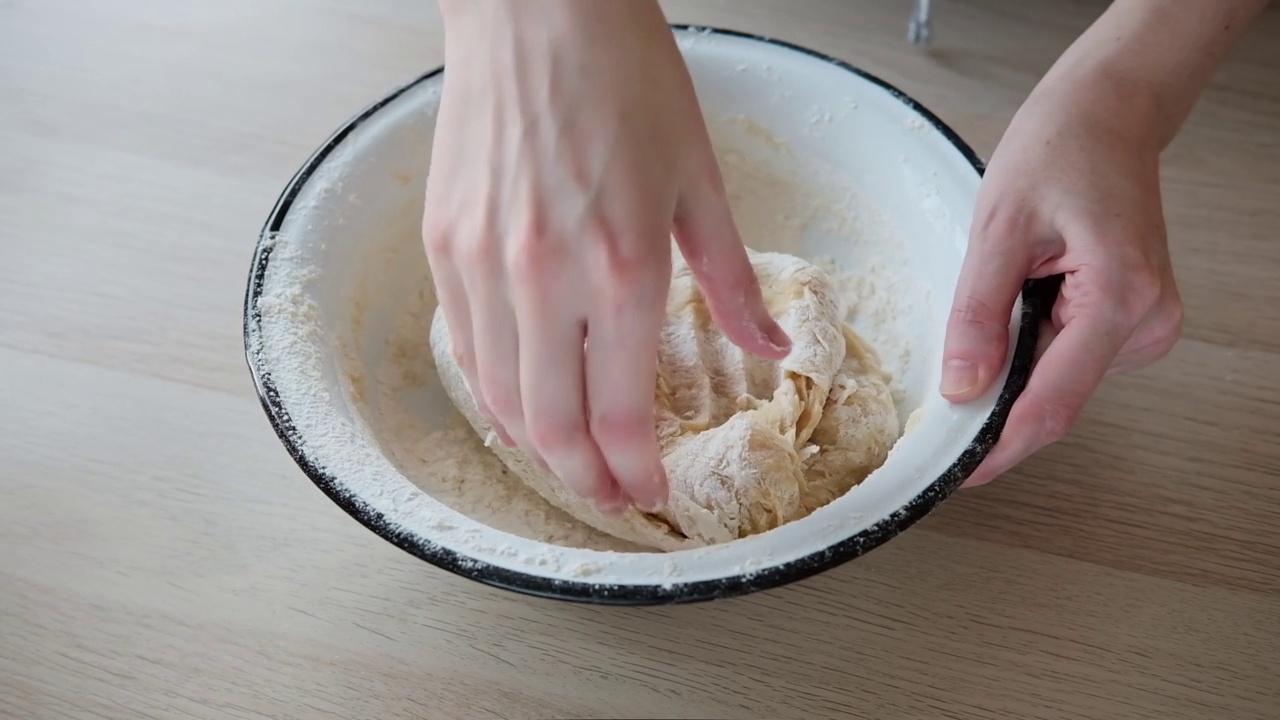 女人的手揉面团准备做馅饼的特写镜头。面团制作:把材料放在桌子上的面团制作馒头的过程视频素材