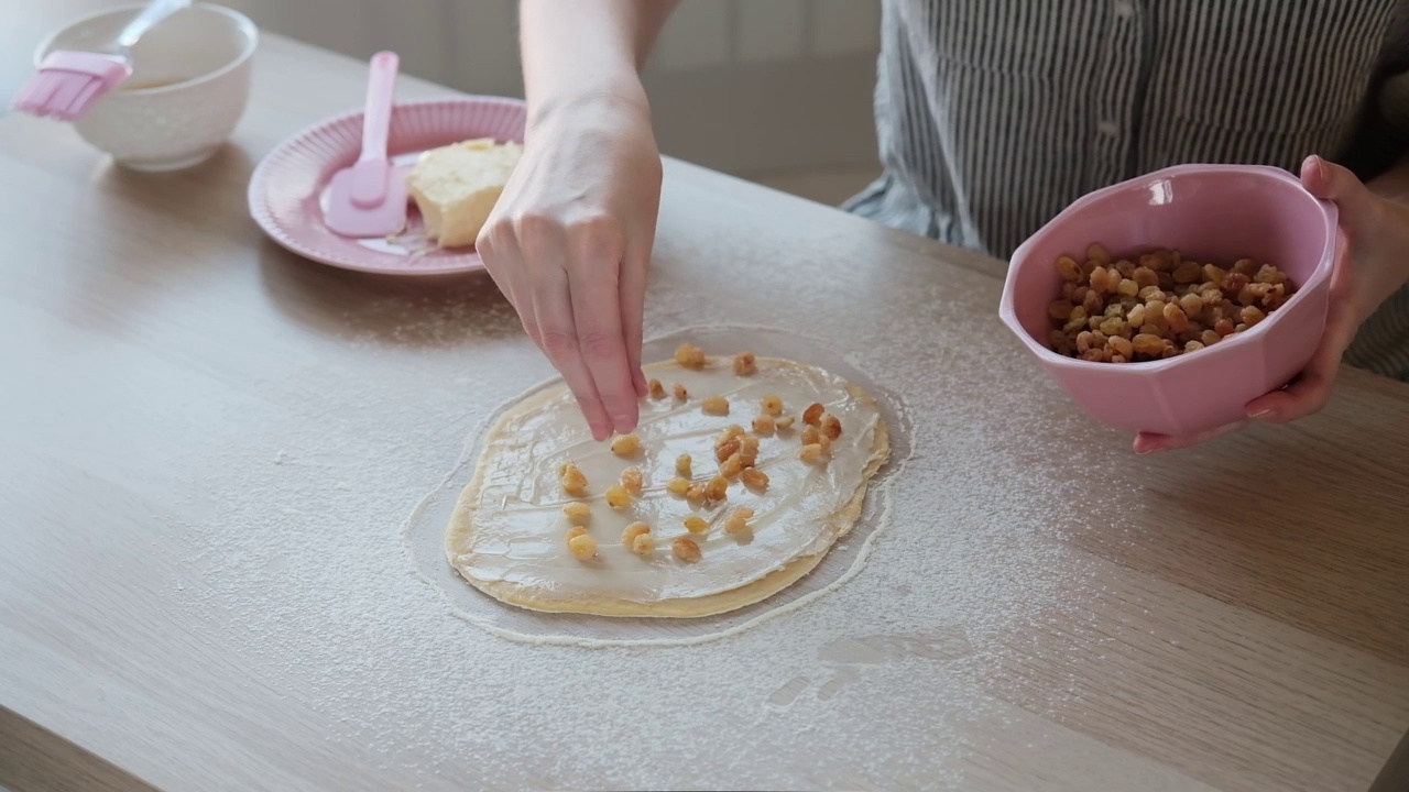 厨师在擀好的面团上撒葡萄干。面团制作:把材料放在桌子上的面团制作馒头的过程视频素材