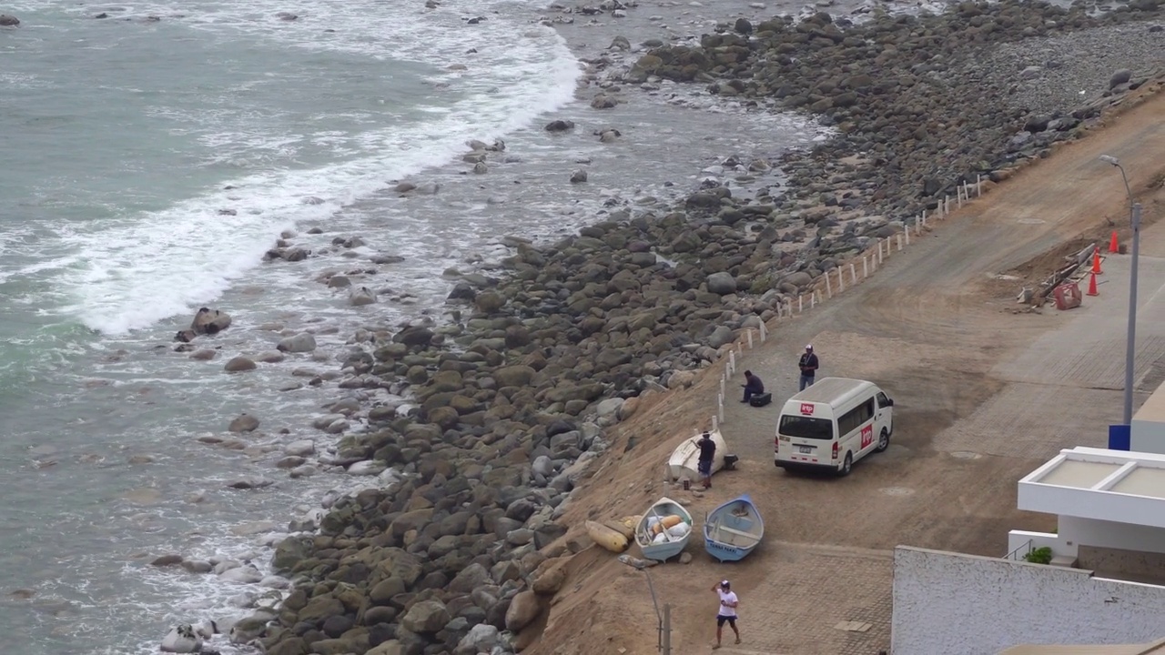 一架IRTP无人机在海滩上飞行，在人群、岩石和海浪中与操作员在4k天-秘鲁蓬塔赫莫萨- 2022年1月视频素材